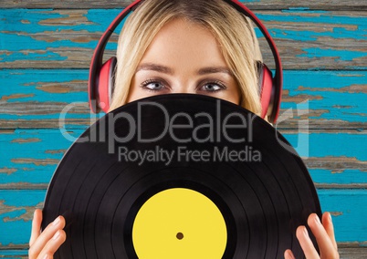 Woman with headphones and record against blue wood panel