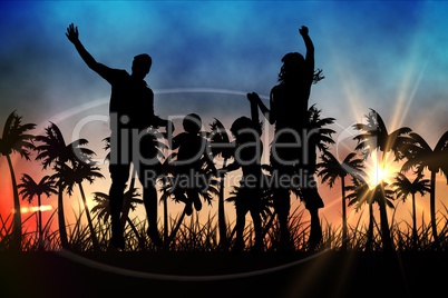 Silhouettes of jumping family  with suitcase against sunset view with palm trees