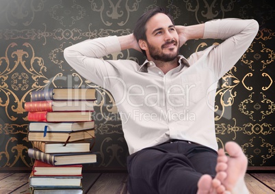 Man sitting relaxed with Books stacked by antique wallpaper decorative