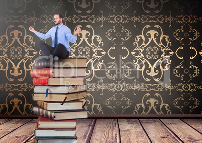 Businessman sitting meditating on Books stacked by decorative wallpaper antique