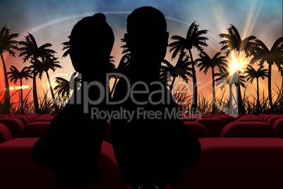 Silhouetts of  couple against 3d  cinema seats facing sunset view with palms