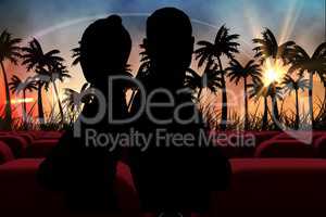 Silhouetts of  couple against 3d  cinema seats facing sunset view with palms