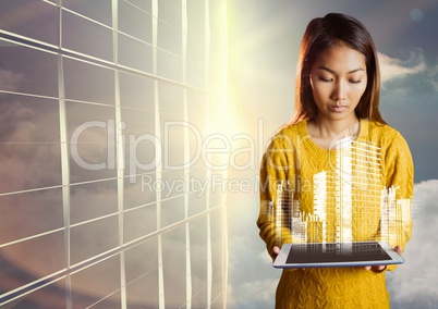 Woman looking down at tablet and white building graphic against window and evening sky