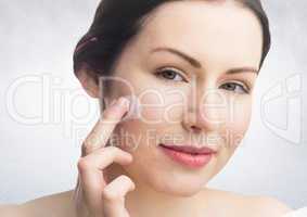 Woman with cream on face against white wall