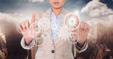 Business woman with white gear graphic between hands against skyline