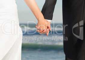 Wedding couple holding hands by sea