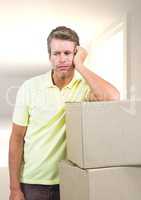 Sad man leaning on cardboard boxes against home