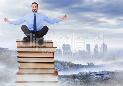 Businessman sitting meditating on Books stacked by distant city
