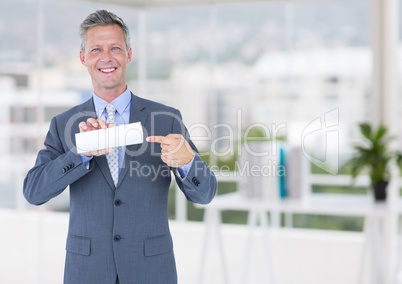 Business man with small blank card in blurry office