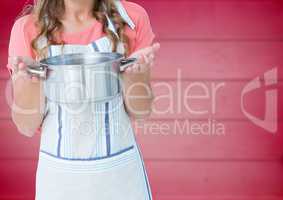 Woman in apron with pan against blurry pink wood panel