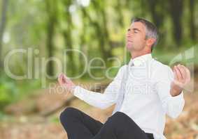 Businessman Meditating by forest