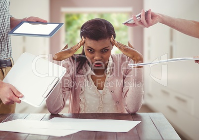 Stressed woman at desk surrounded by technology  devices and files in room