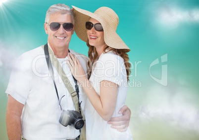 Couple in summer clothes against blue green background with clouds and flare