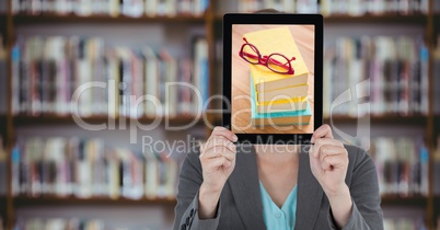Business woman with tablet over her face with piles of books while standing at  library