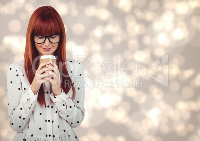 Woman in polka dot shirt looking down at coffee cup against cream bokeh