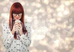 Woman in polka dot shirt looking down at coffee cup against cream bokeh