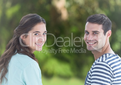 Couple looking over shoulders against blurry green background