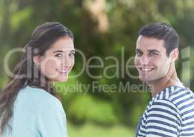 Couple looking over shoulders against blurry green background