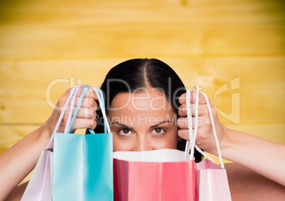 Woman with shopping bags against yellow wood panel