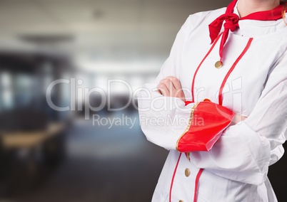 Chef arms folded against blurry restaurant