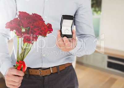 Man holding engagement ring and flowers in room