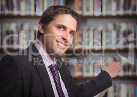 Business man gesturing towards blurry bookshelf