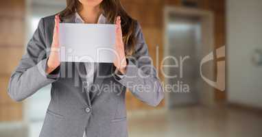 Business woman mid section with blank card against blurry elevators