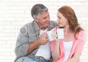 Man and woman with white mugs against white brick wall