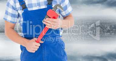 Handyman with red wrench against blurry skyline