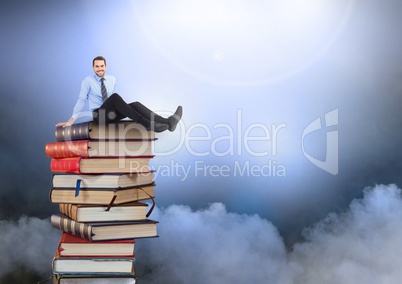 Businessman sitting on Books stacked by atmospheric clouds