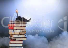 Businessman sitting on Books stacked by atmospheric clouds