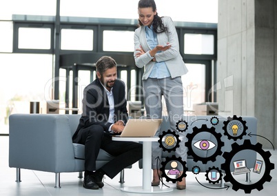 Business man and woman looking at laptop with black gear graphics