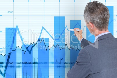 Business man writing on wall with financial graphs