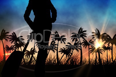 Silhouettes of lady with suitcase against sunset view with palm trees