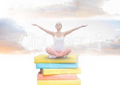 Girl meditating on Books stacked by brick wall