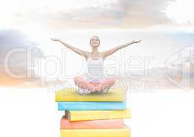Girl meditating on Books stacked by brick wall