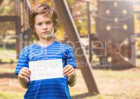 Sad boy holding help sign against playground