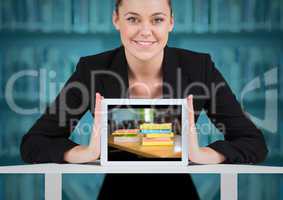 Business woman with tablet showing book pile against blurry bookshelf with blue overlay