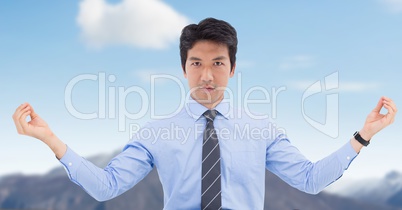 Businessman Meditating against blue sky mountain