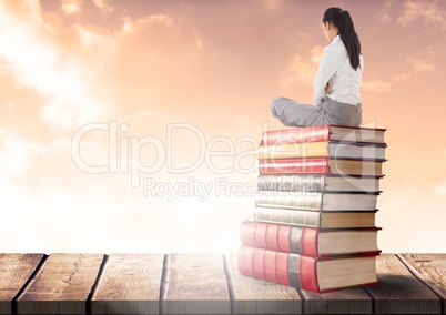 Businesswoman sitting on Books stacked by sunny clouds