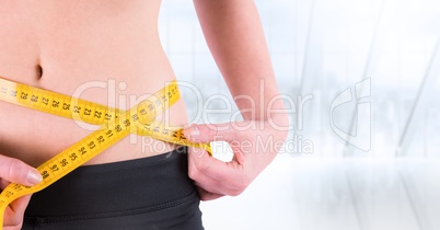 Woman torso with measuring tape against blurry window