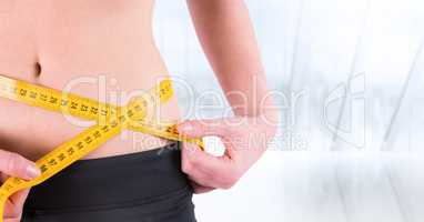 Woman torso with measuring tape against blurry window