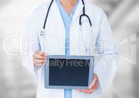 Doctor mid section with tablet against blurry background