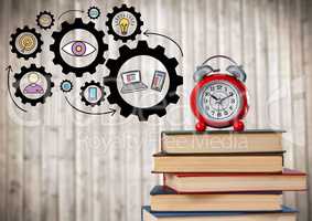 Pile of books and clock with gear graphics against blurry wood panel