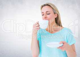 Woman drinking from white cup against white wall