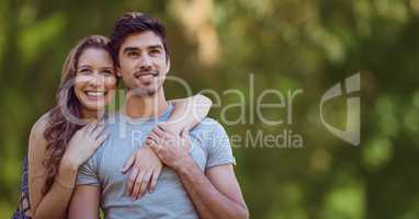 Woman with arms around man against blurry green background