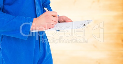 Mechanic with clipboard against blurry yellow wood panel