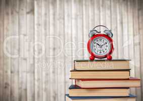 Pile of books and clock against blurry wood panel