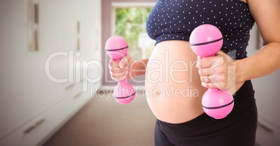 Pregnant woman mid section with pink weights in blurry hallway