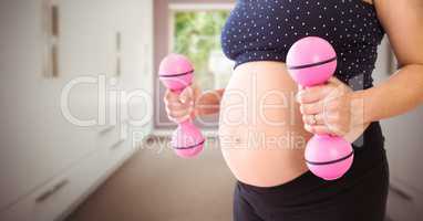 Pregnant woman mid section with pink weights in blurry hallway